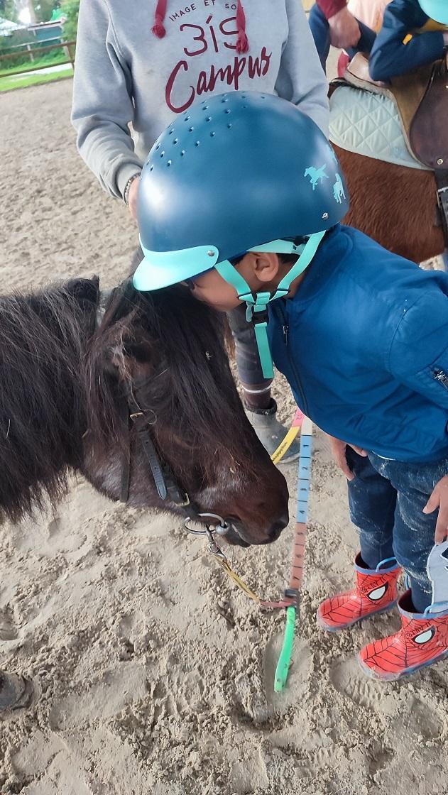 Équitation adaptée — un petit embrasse un poney